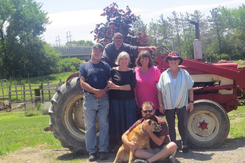 Zach Beaudoin with family and dog in front of a tractor on the farm