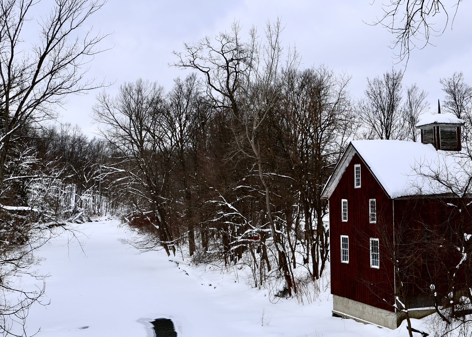 Historic red barn nestled among trees in a snowy Eden landscape