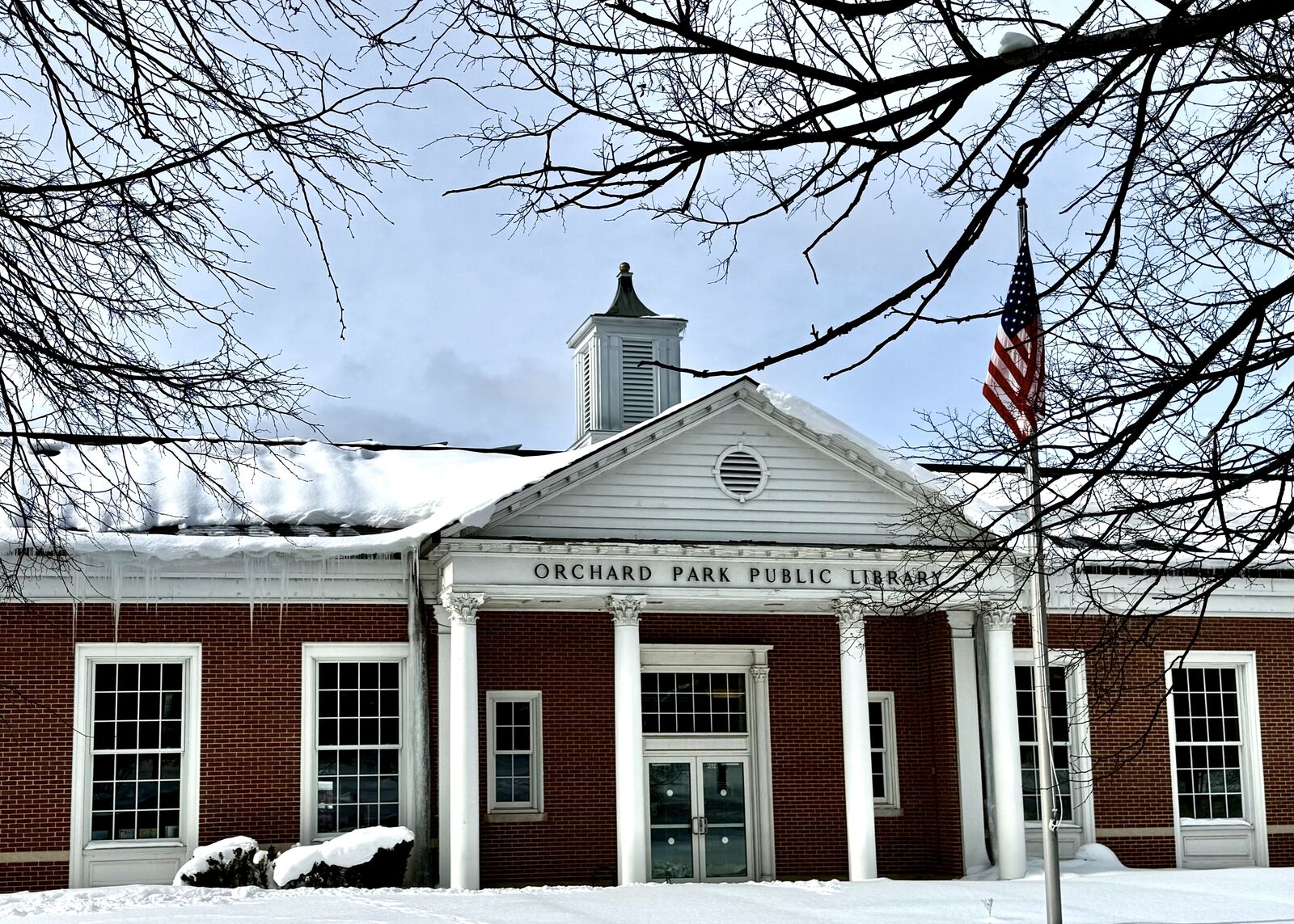 Orchard Park Public Library in winter with American flag